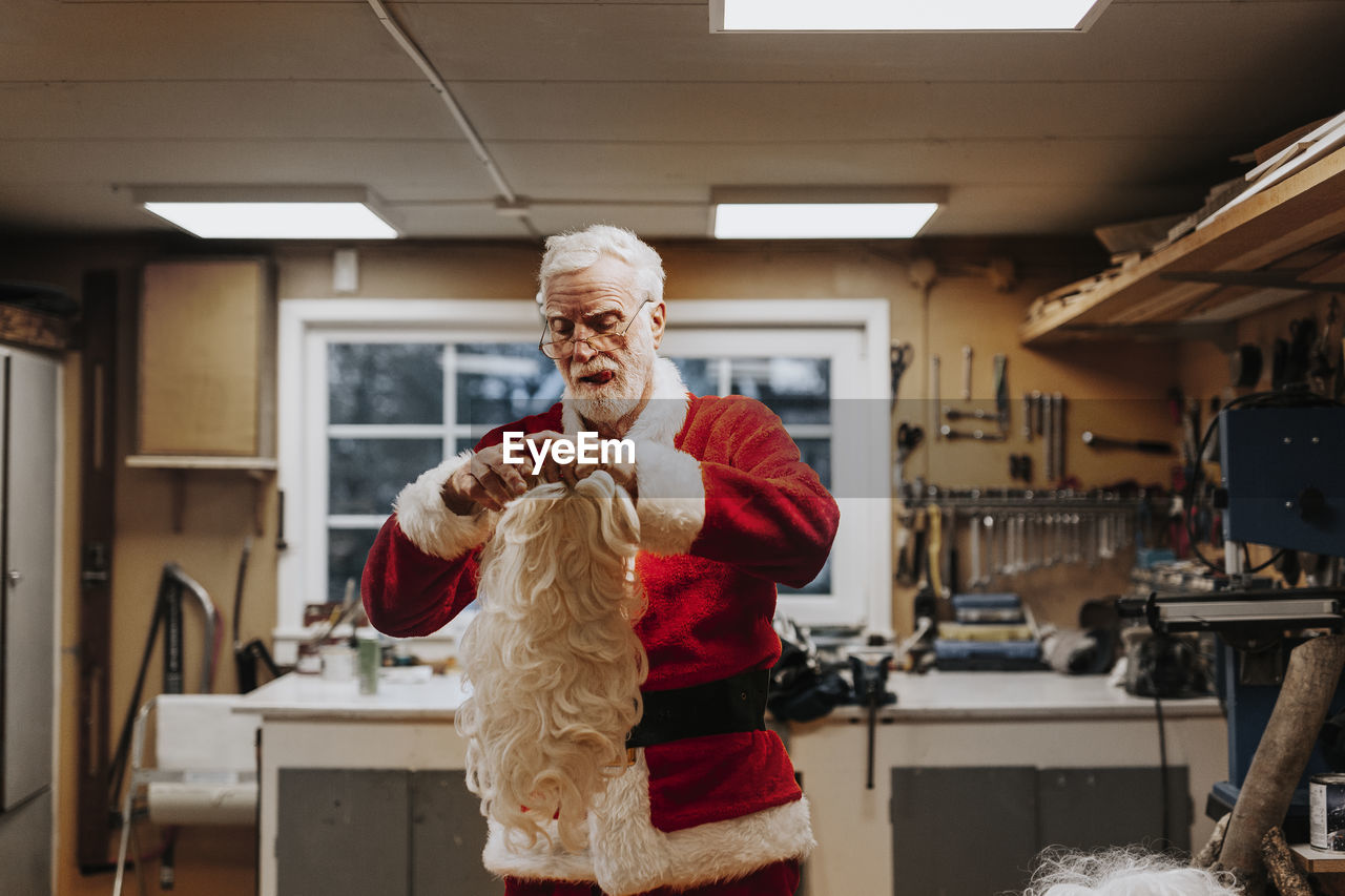 Senior man putting santa costume on