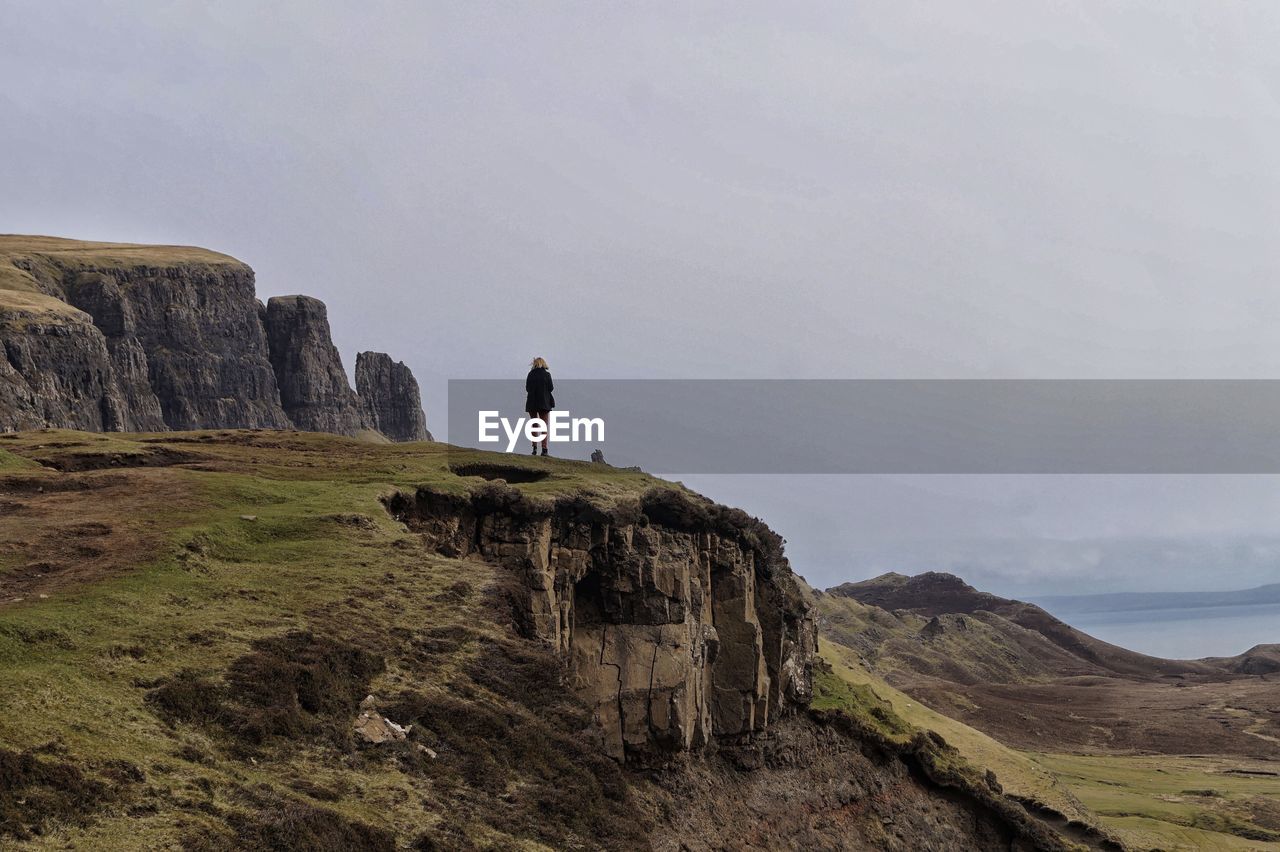 Rear view of woman standing on cliff