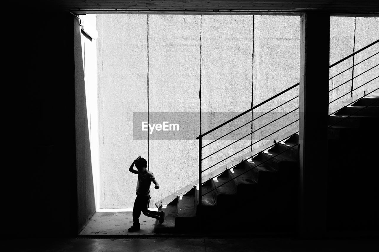 Silhouette side view of young kid walking on concrete staircase