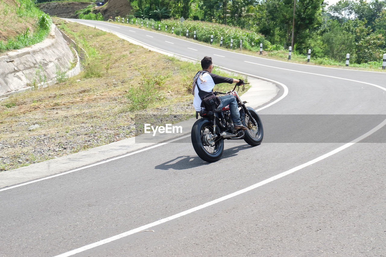 WOMAN RIDING MOTORCYCLE ON ROAD