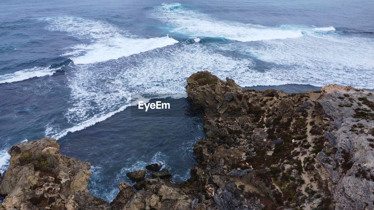 sea, water, rock, beach, wave, coast, shore, ocean, beauty in nature, land, wind wave, cliff, motion, surfing, scenics - nature, water sports, sports, nature, rock formation, high angle view, terrain, day, outdoors, body of water, coastline, splashing, breaking, tranquility, bay, cove