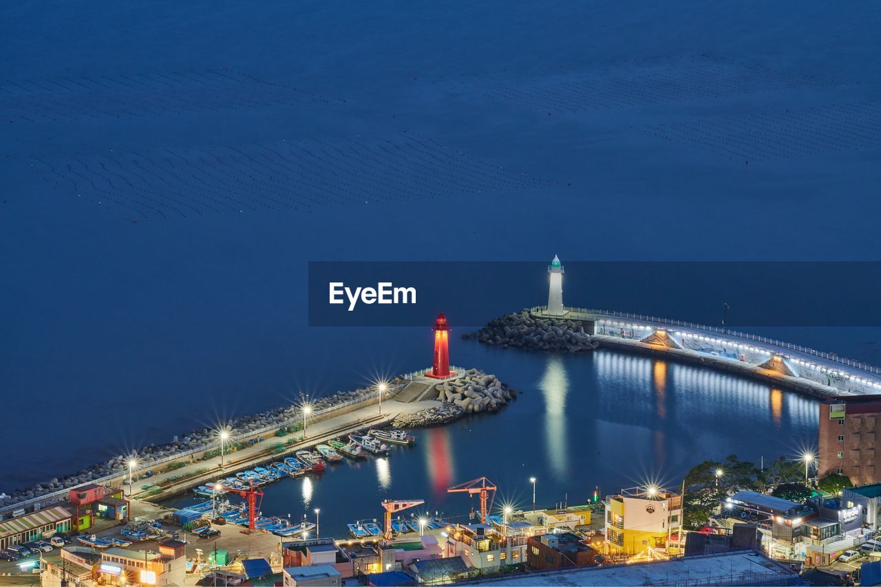 HIGH ANGLE VIEW OF ILLUMINATED COMMERCIAL DOCK AGAINST SKY AT NIGHT