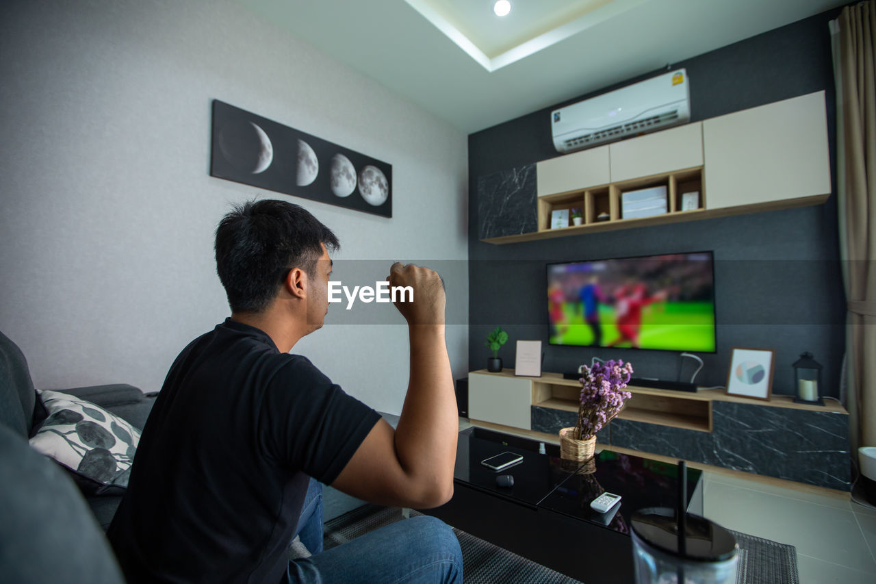 Side view of man sitting on table at home