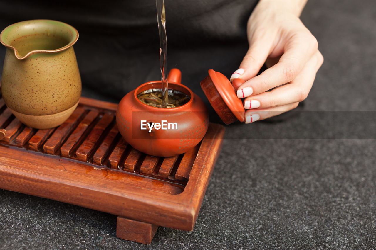 Cropped hand pouring water in tea