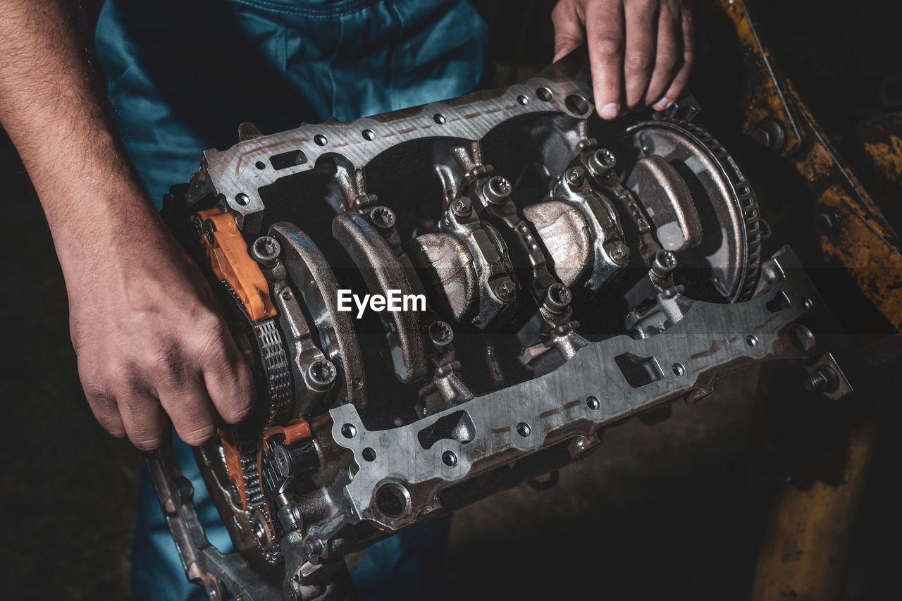 Hands of auto mechanic and disassembled engine, closeup. car maintenance