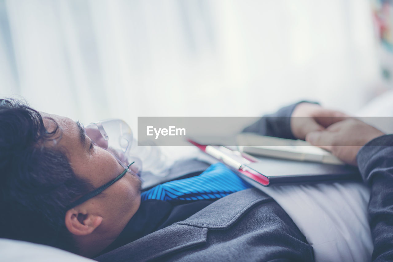 Businessman with oxygen mask lying at hospital