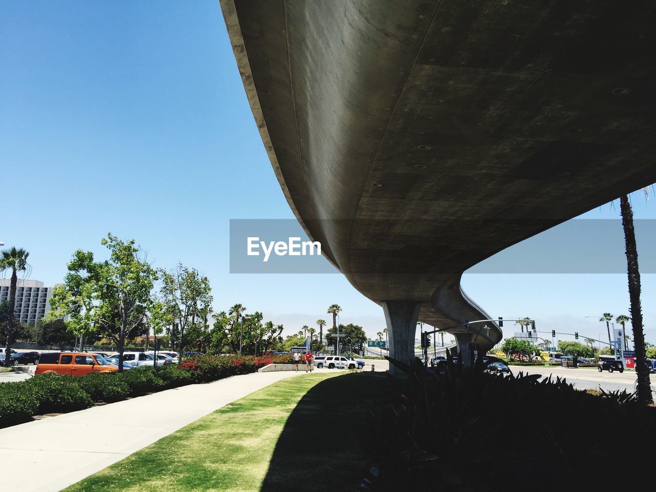 Low angle view of bridge over street in city against clear blue sky