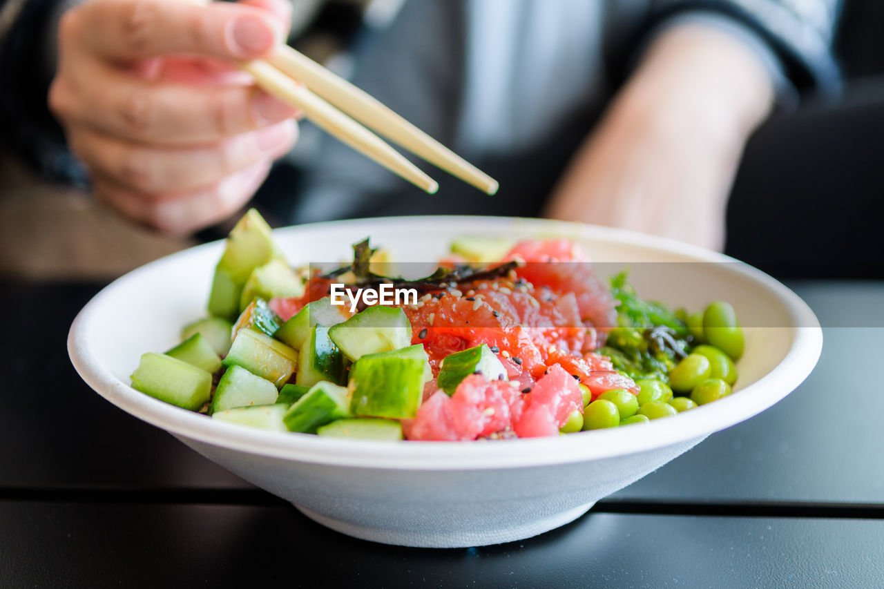 Midsection of person eating salad