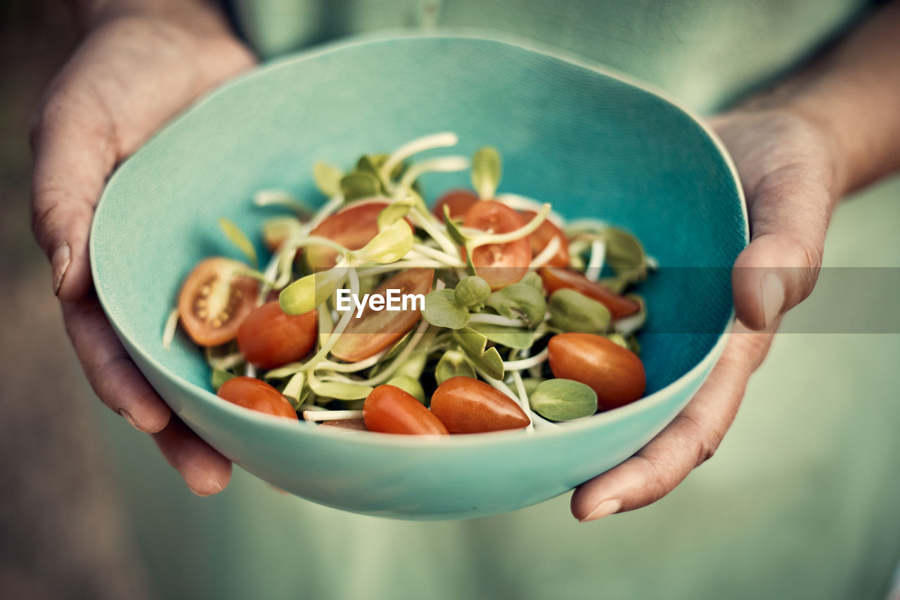 CLOSE-UP OF PERSON HOLDING SALAD