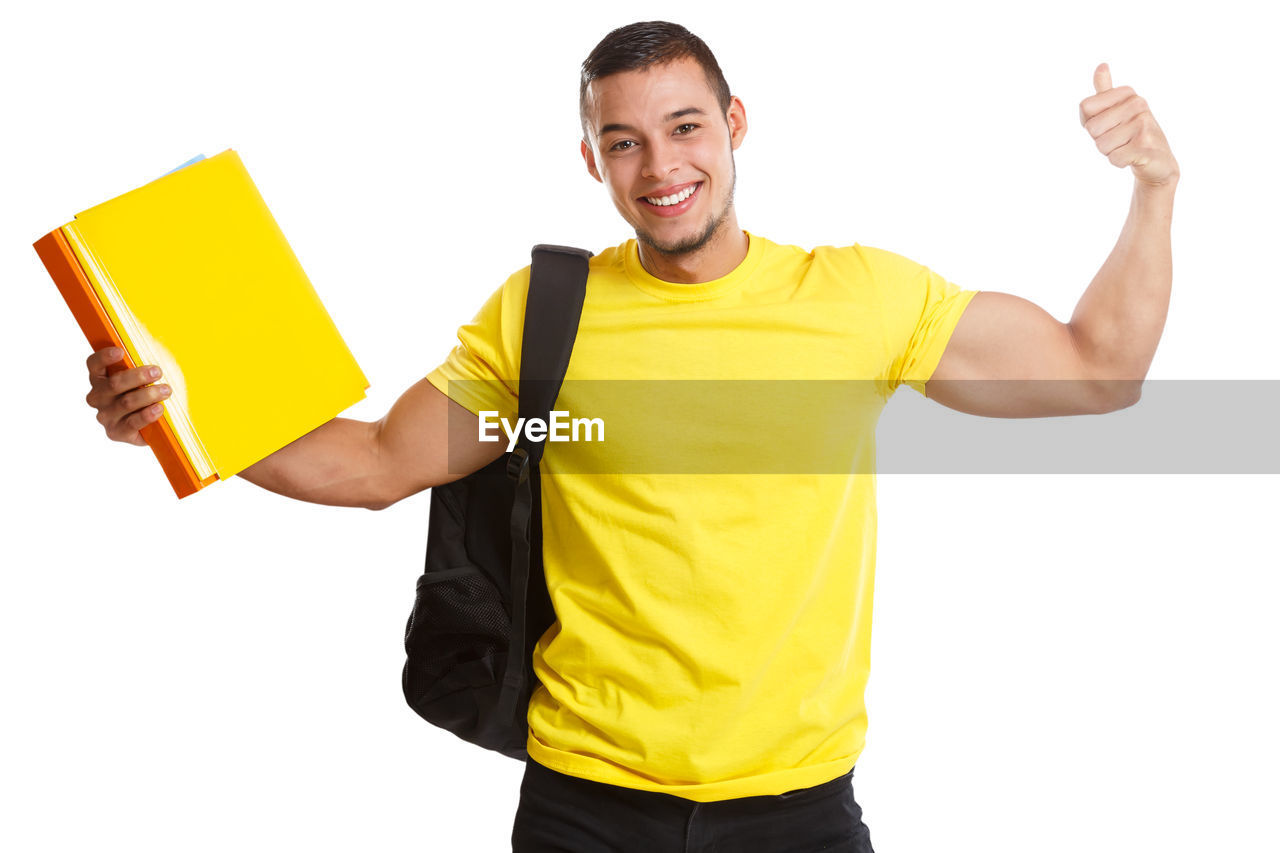 PORTRAIT OF YOUNG MAN STANDING AGAINST YELLOW BACKGROUND