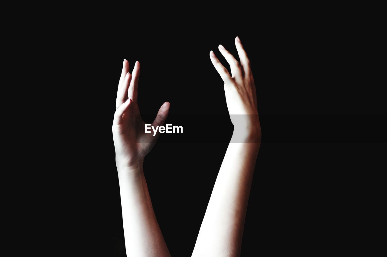 Cropped hands of woman gesturing against black background