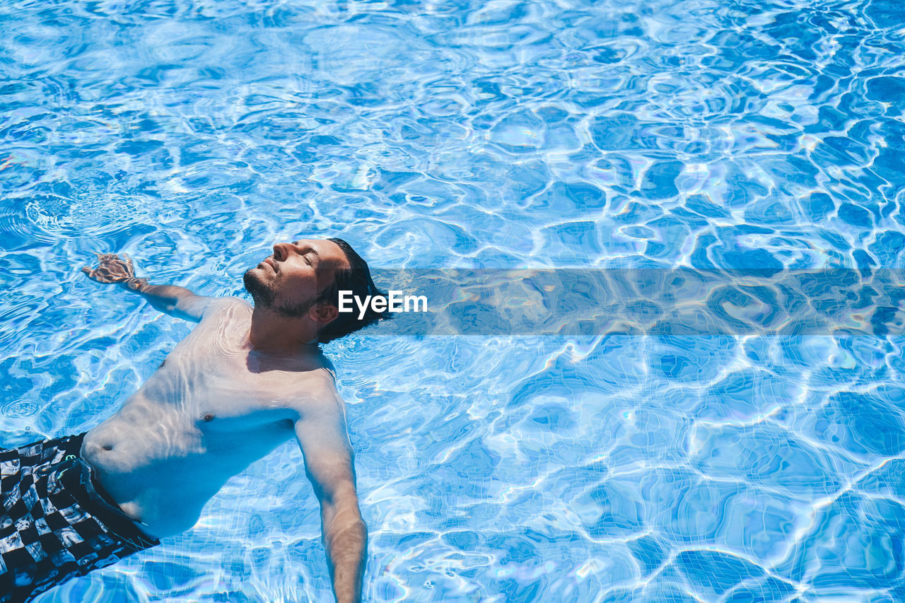 Full length of shirtless man in swimming pool