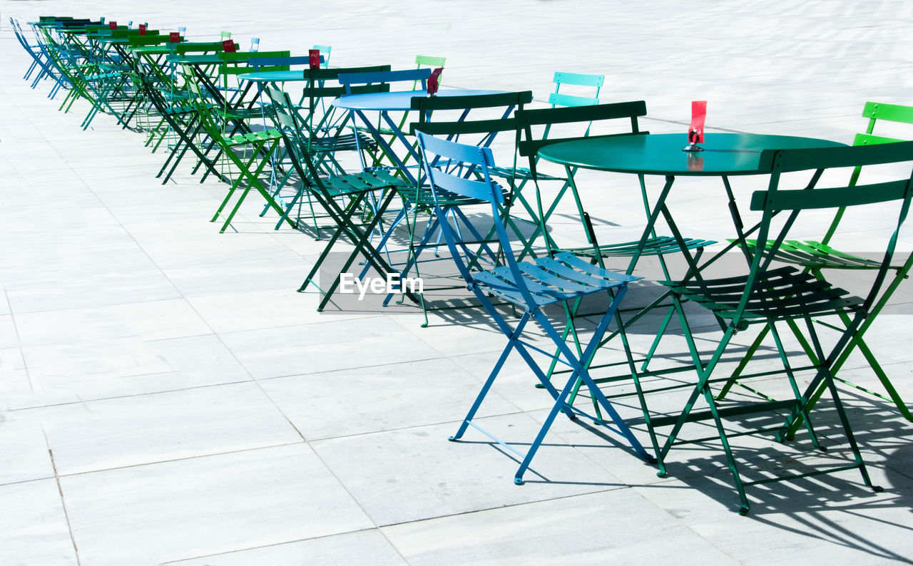 Row of colorful tables and chairs in perspective.