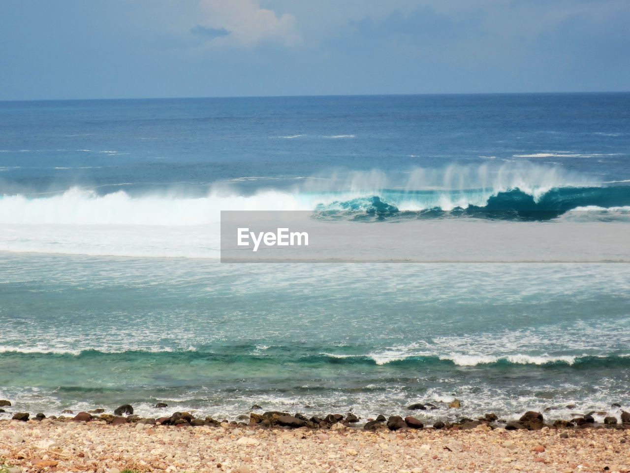 WAVES SPLASHING ON SHORE AGAINST SKY