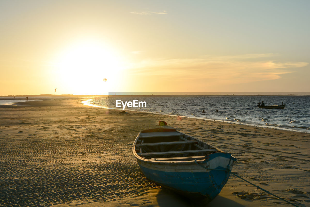 Boat moored at seashore during sunset