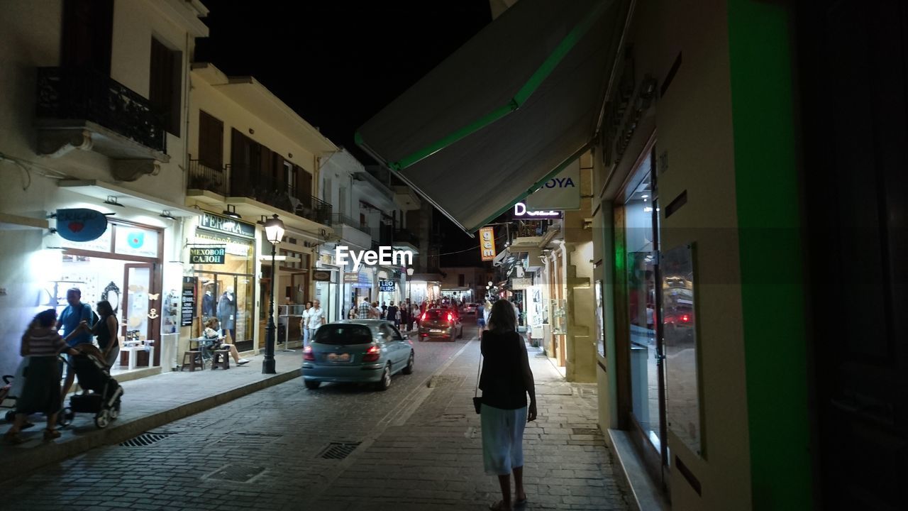 PEOPLE AT ILLUMINATED CITY AT NIGHT