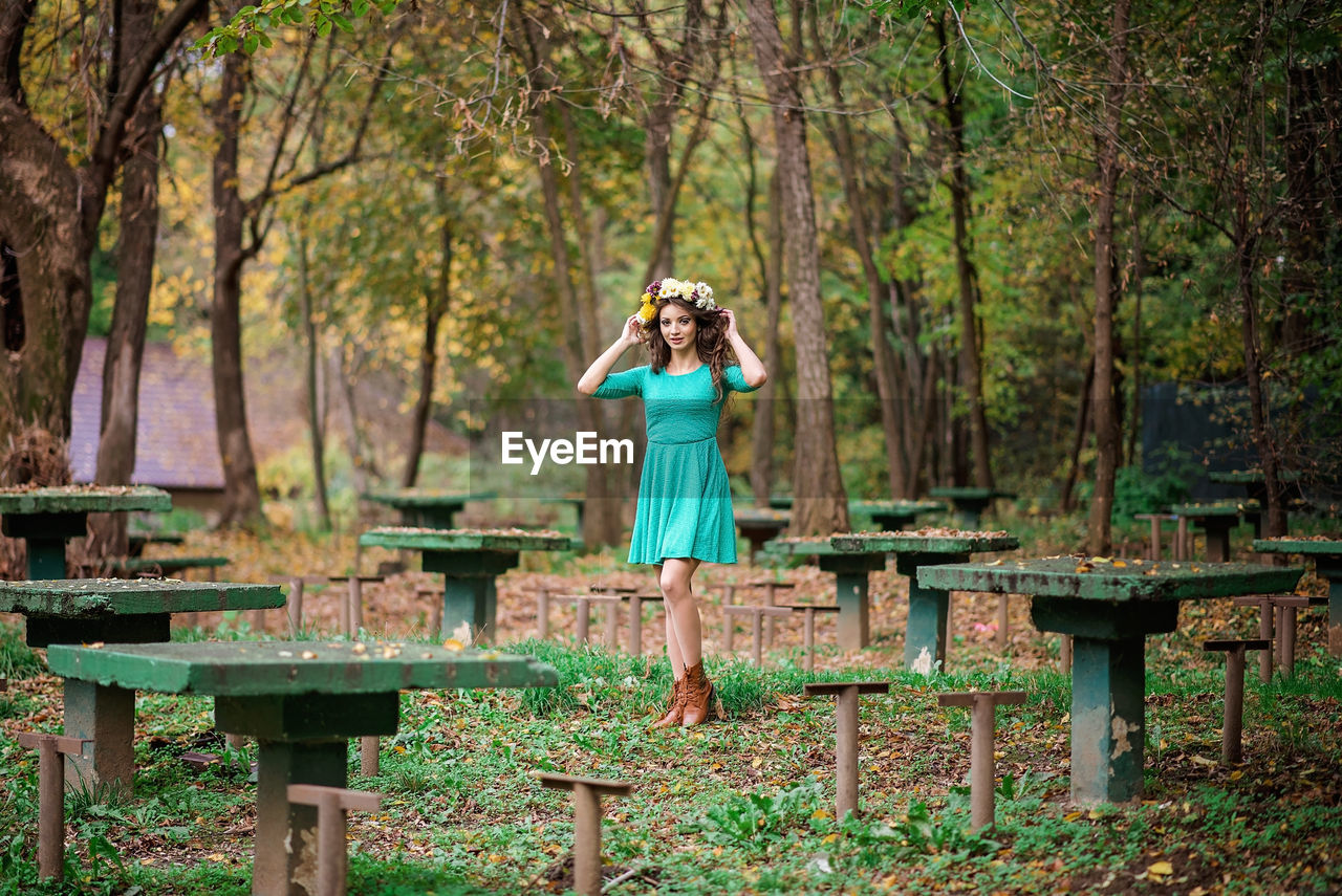 Portrait of beautiful woman wearing flowers standing in forest