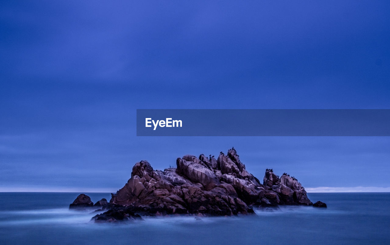 Rock formations in sea against blue sky