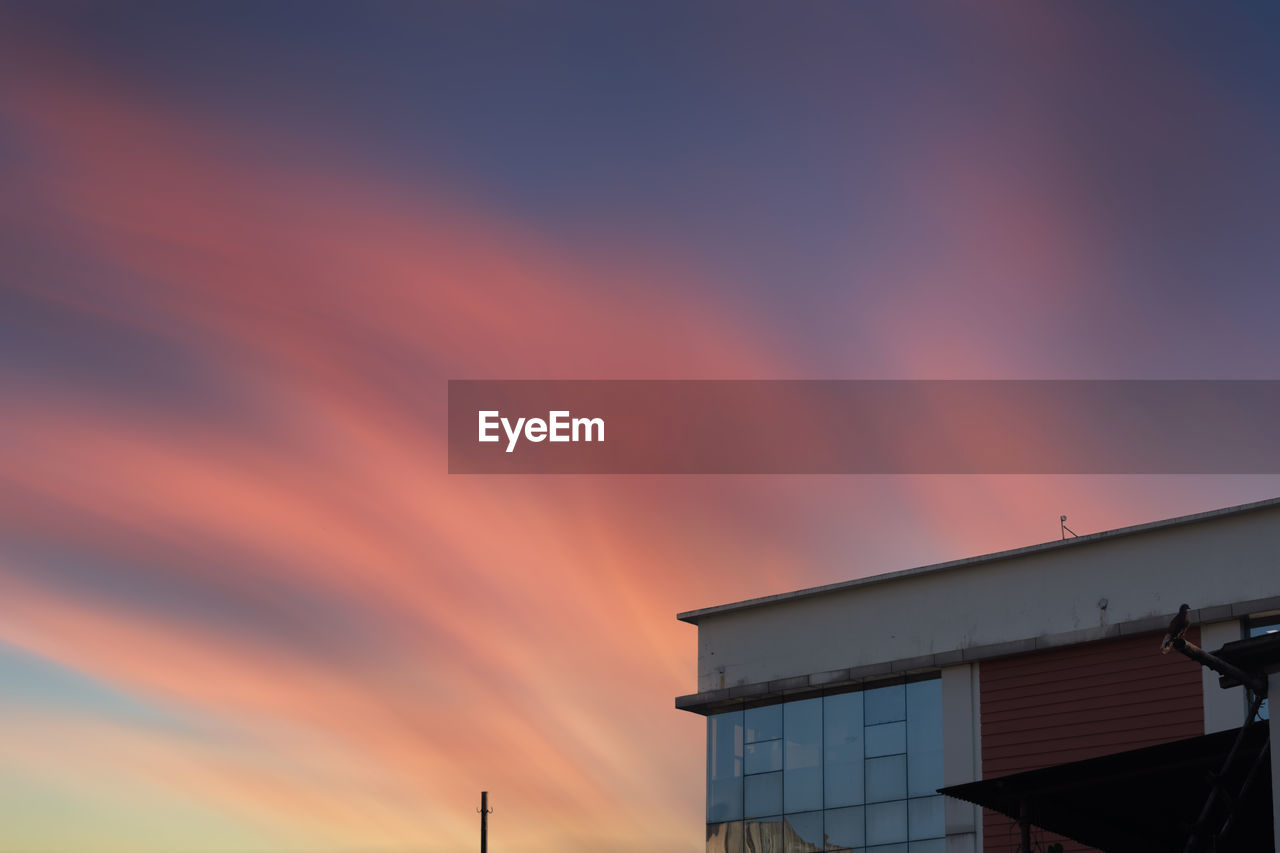 LOW ANGLE VIEW OF BUILDING AGAINST SKY AT SUNSET