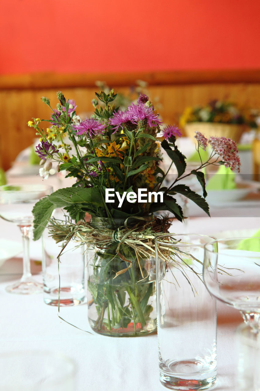 CLOSE-UP OF FLOWER VASE ON TABLE AGAINST GLASS WALL