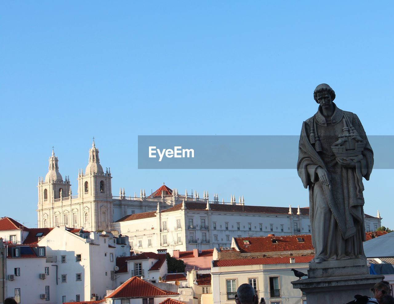 STATUE AGAINST BLUE SKY AND BUILDINGS IN CITY AGAINST CLEAR BACKGROUND
