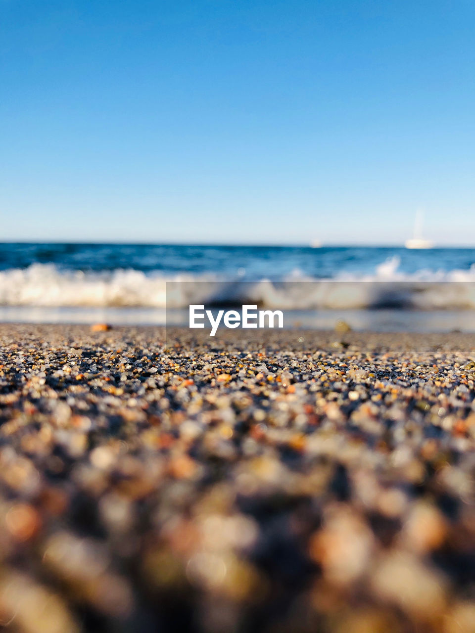 Surface level of pebble beach against clear sky