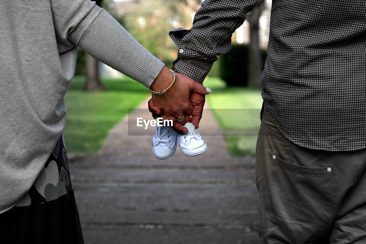 Midsection of couple with baby booties in park