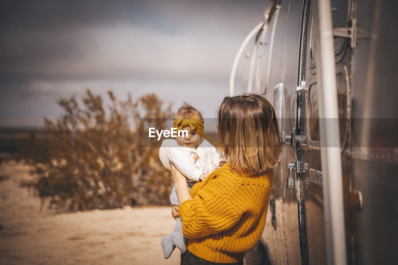 A woman with a baby is near an rv trailer, joshua tree, california