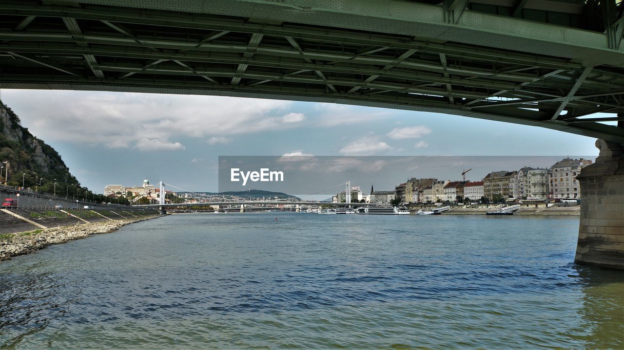 Bridge over river in city against sky