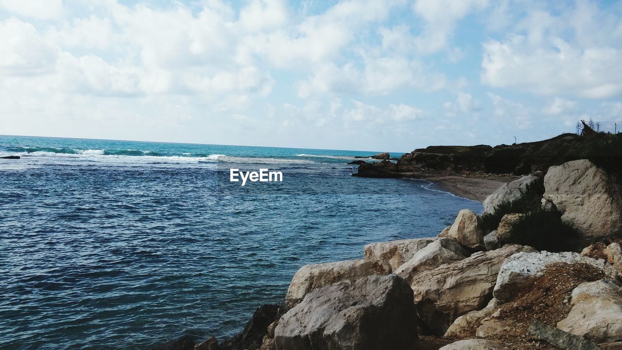 View of calm blue sea against cloudy sky