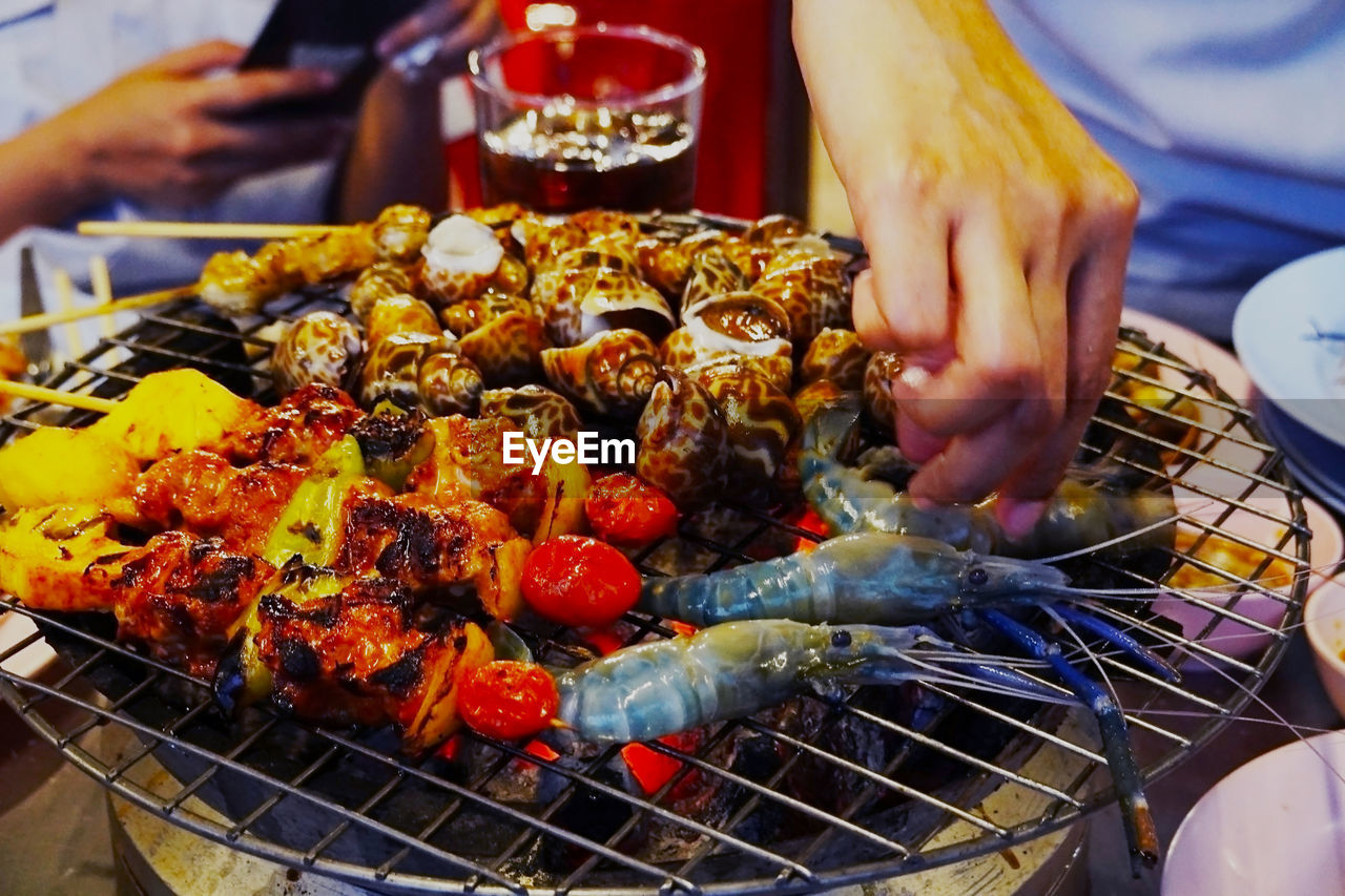 Midsection of person preparing food on barbecue