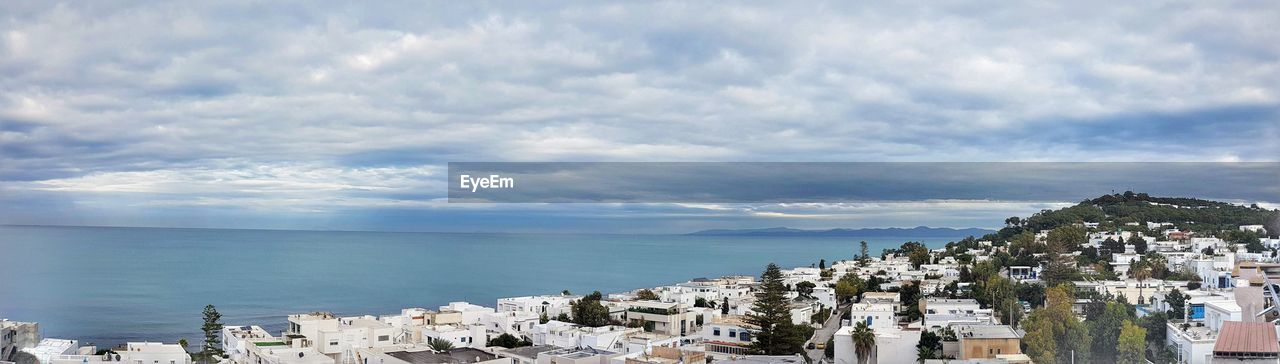 PANORAMIC VIEW OF SEA BY BUILDINGS AGAINST SKY