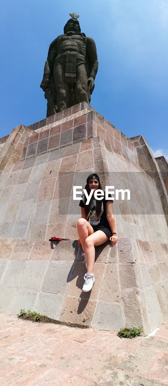 LOW ANGLE VIEW OF YOUNG WOMAN SCULPTURE AGAINST SKY