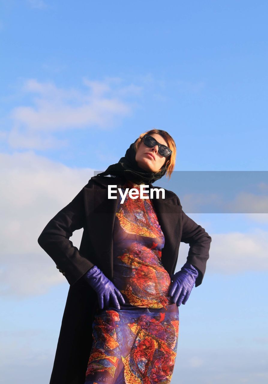 Portrait of young woman standing against sky