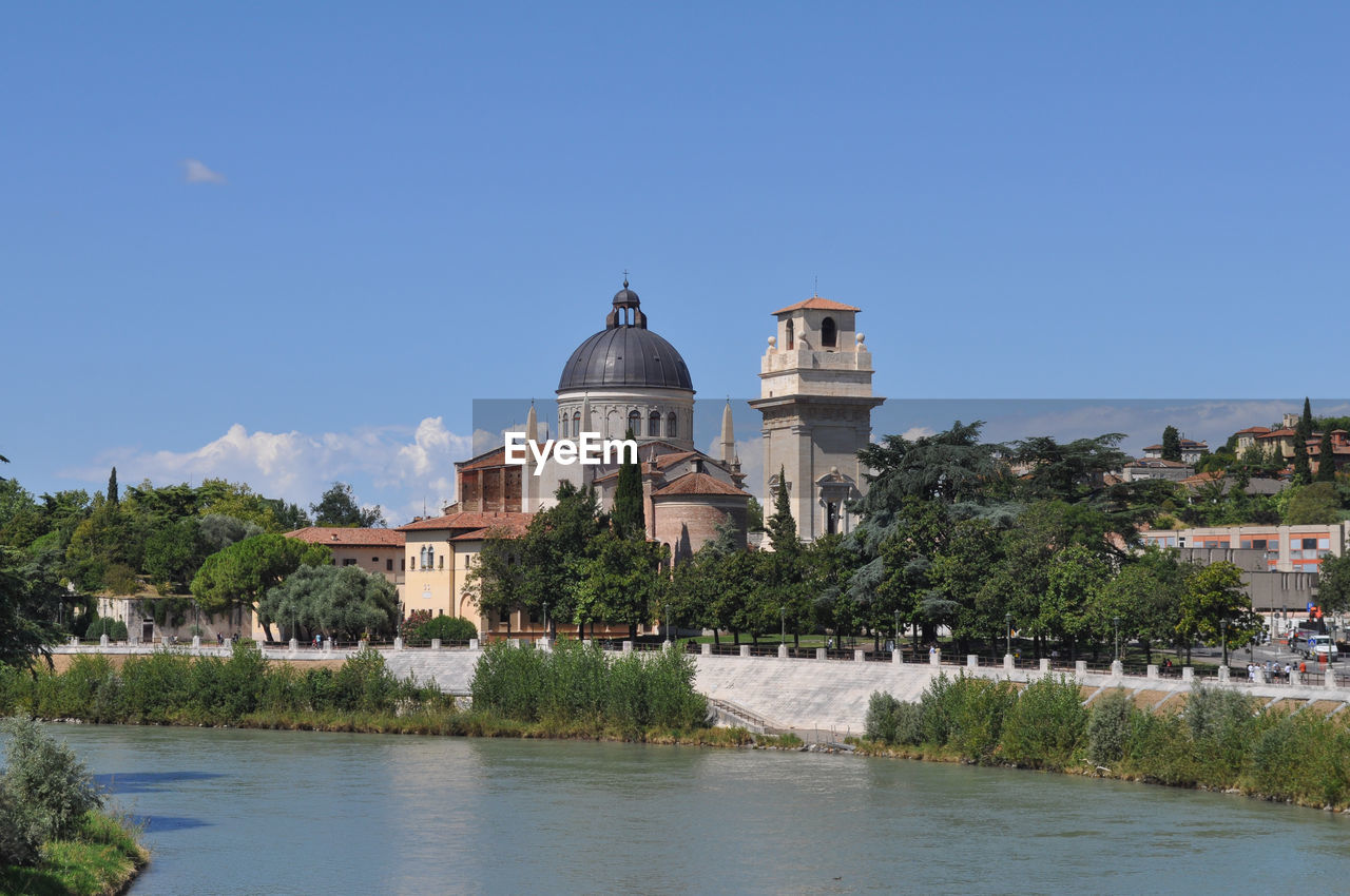 buildings by river against clear blue sky