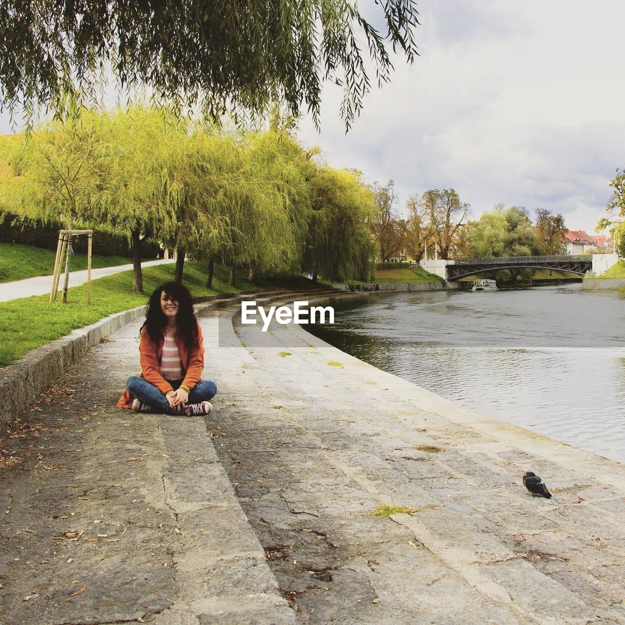 Young woman sitting on steps by lake at park