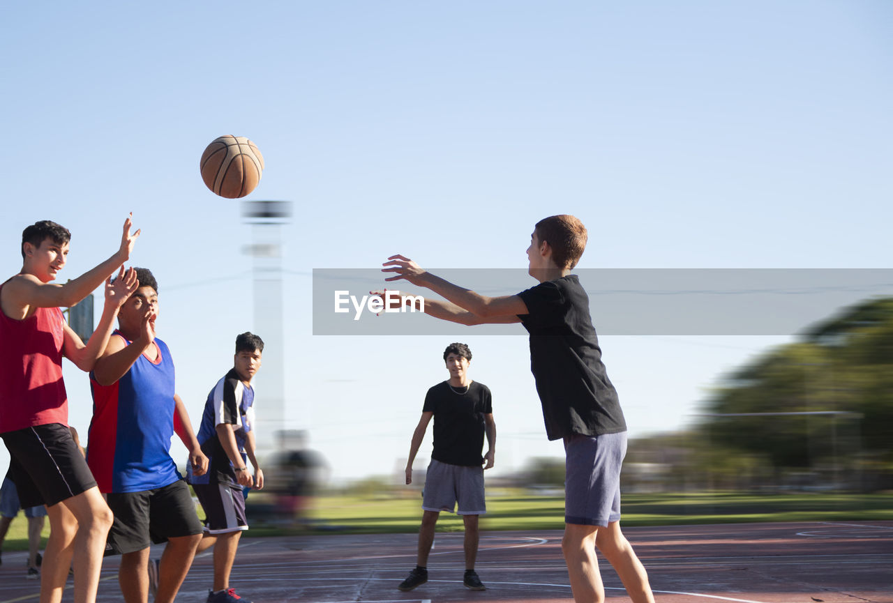 Group of teenagers playing street basketball