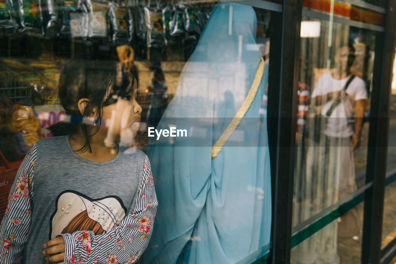 Girl looking through window in store