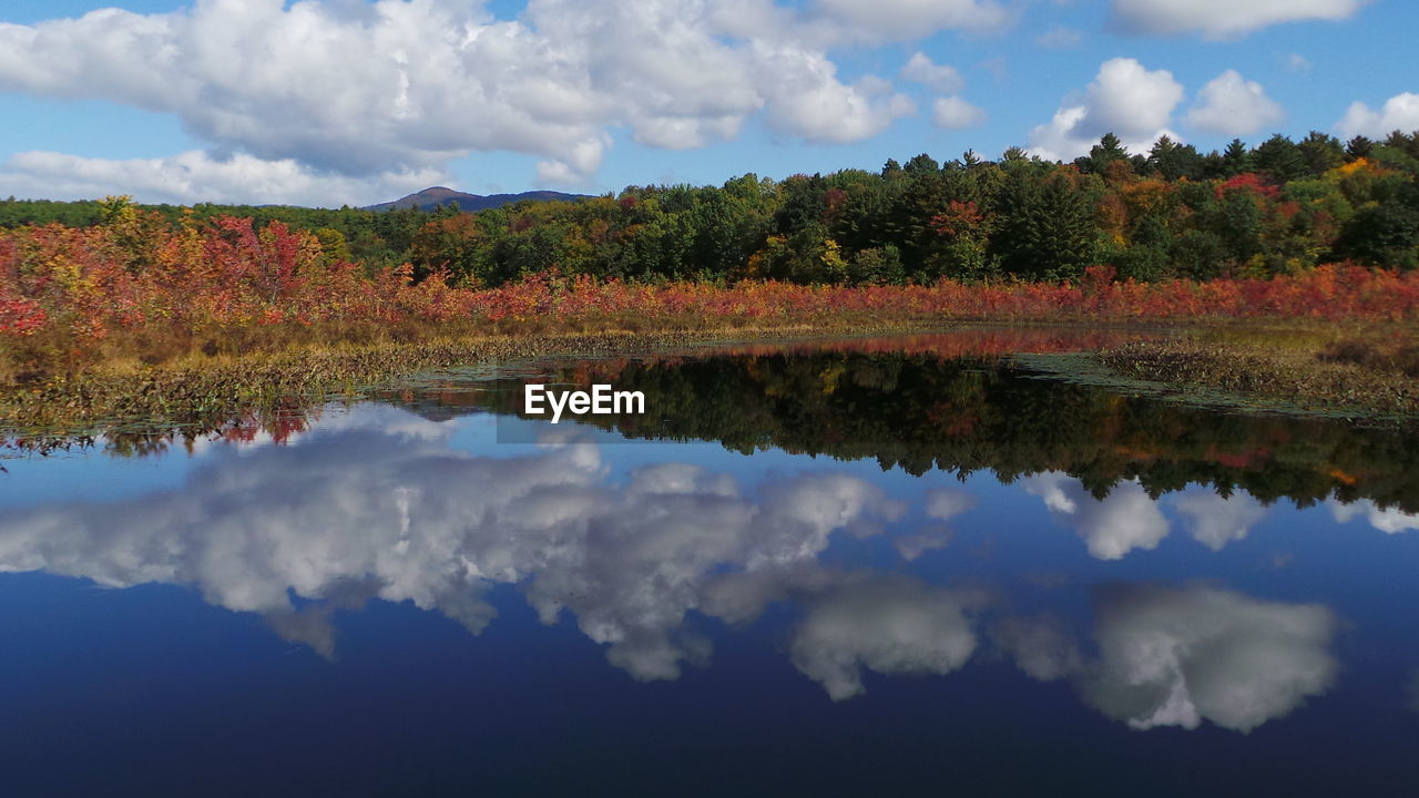 Reflection of clouds in calm lake against cloudy sky