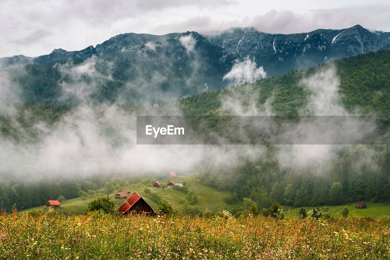 Scenic view of village against mountain against cloudy sky