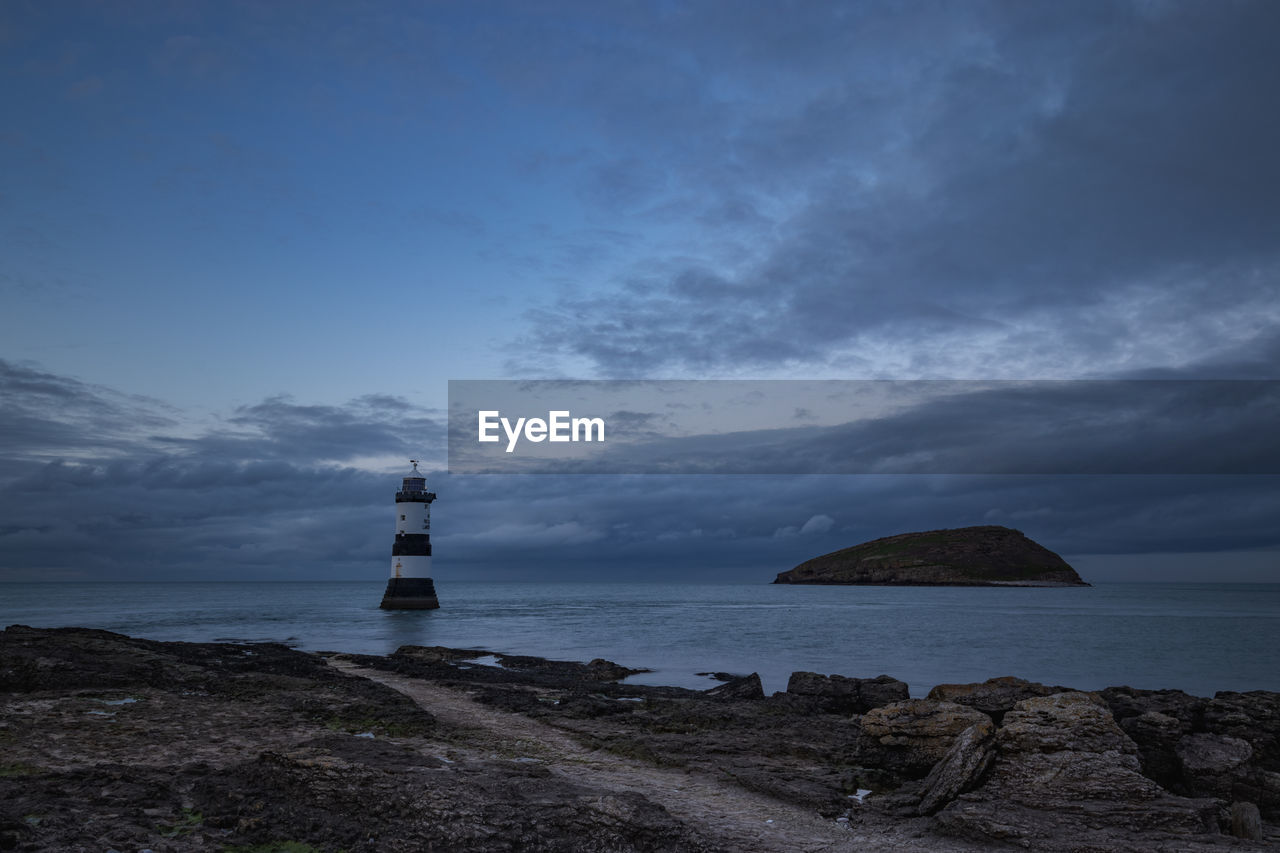 Lighthouse by sea against sky