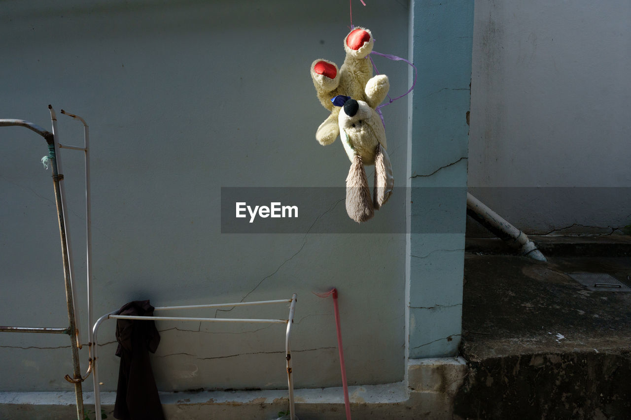 ABANDONED TOY ON WALL BY WATER