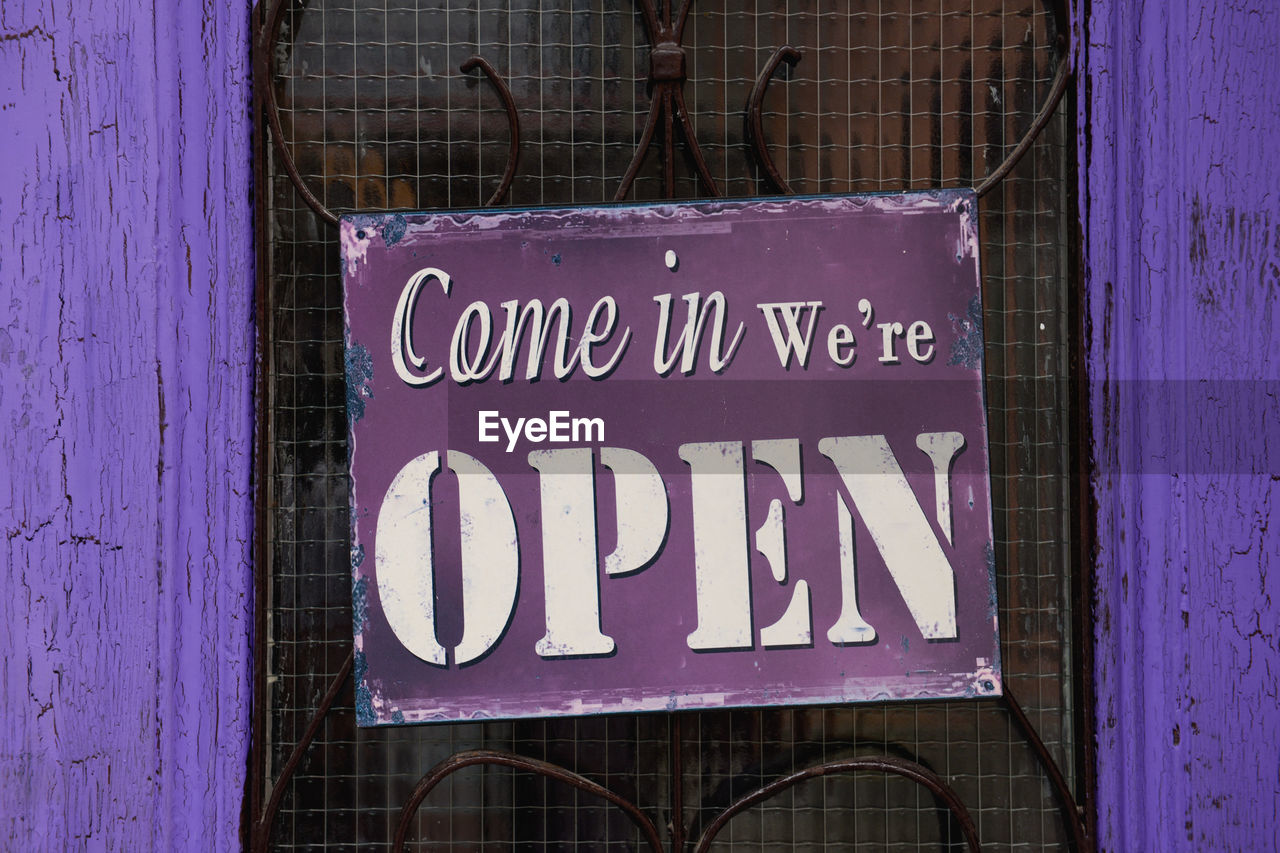 Open sign hanging on purple door