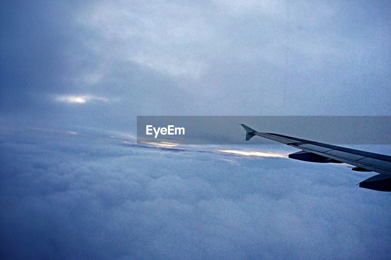 View of airplane wing flying above clouds