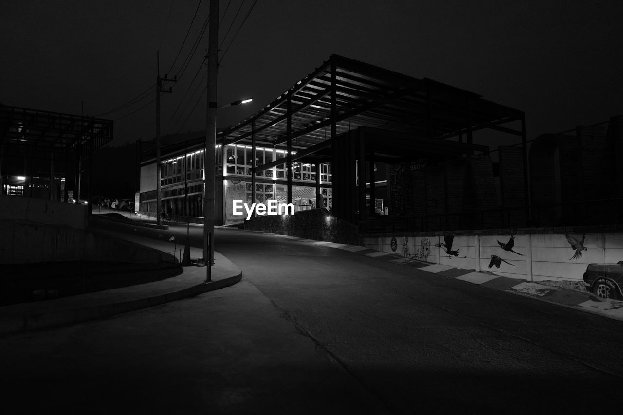 EMPTY ROAD BY BUILDING AGAINST SKY AT NIGHT