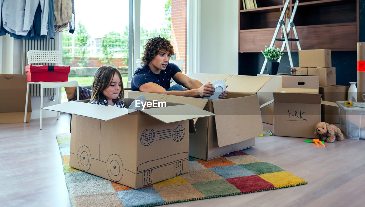 Father and son with plates sitting in cardboard boxes at home