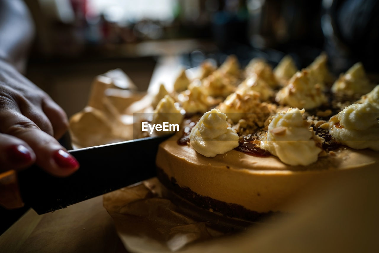 A knife cutting a sweet toffee caramel cake with nuts served as dessert, birthday celebration