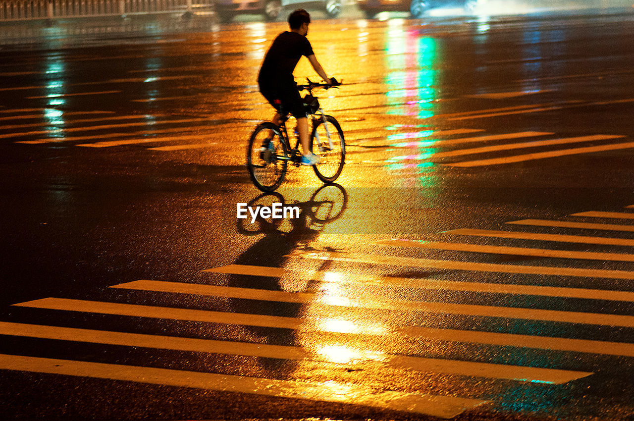 Man riding bicycle on highway at night