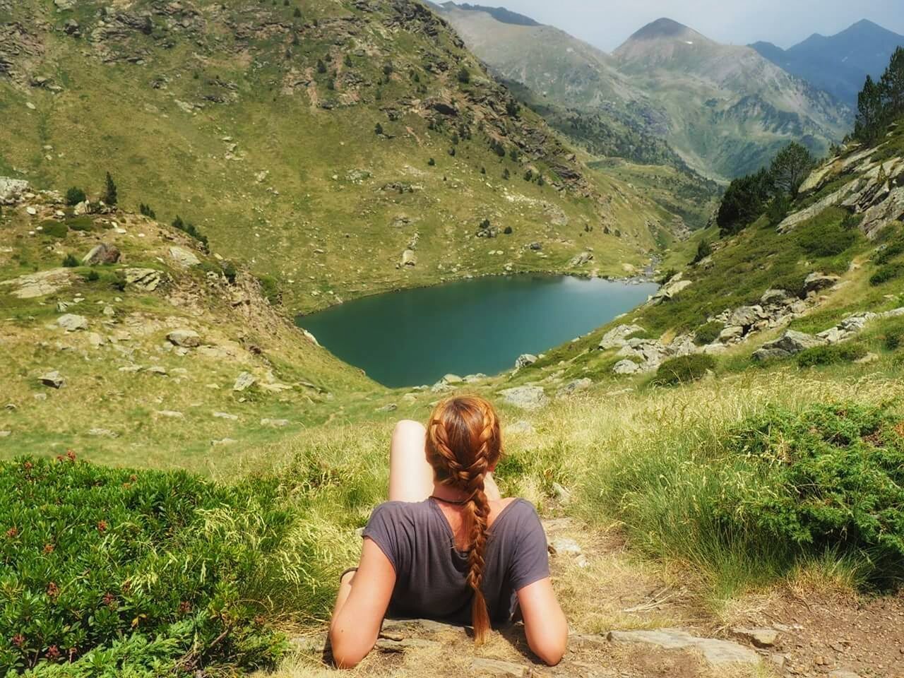 REAR VIEW OF WOMAN SITTING ON MOUNTAIN