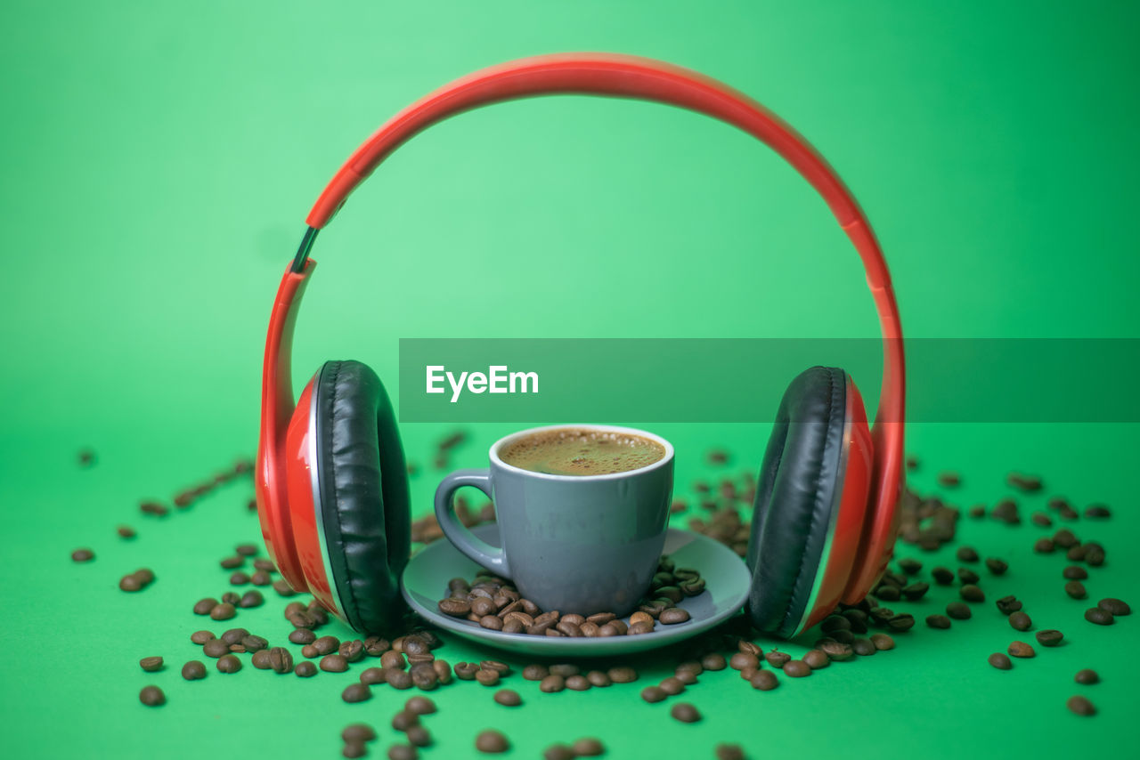 CLOSE-UP OF COFFEE CUP ON TABLE AGAINST GREEN BACKGROUND